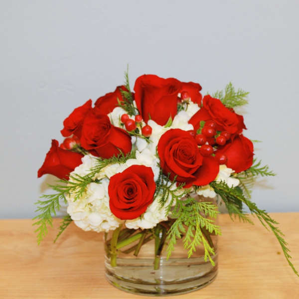 Red roses and white flowers arranged in a clear glass vase
