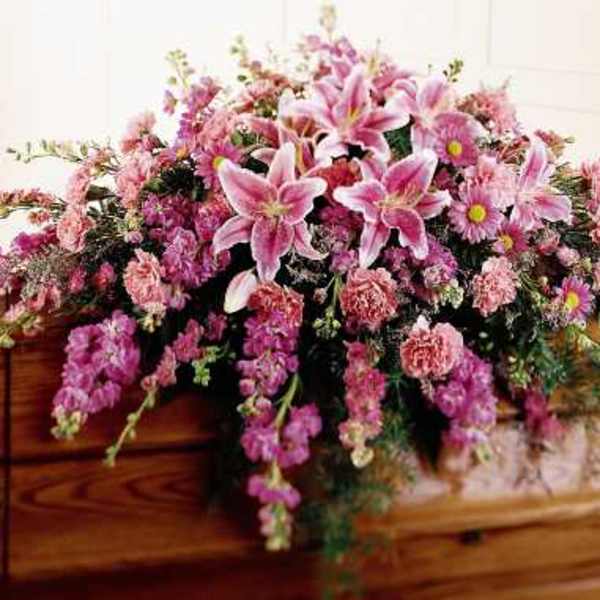 Pink floral spray arranged on a wooden casket
