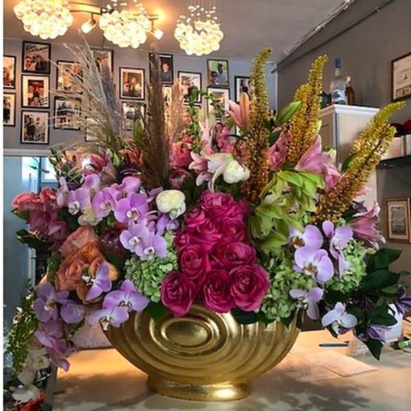 Large floral arrangement with pink roses and purple orchids in a gold vase