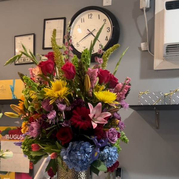 Tall mixed bouquet in a metallic vase with roses, lilies, and hydrangeas