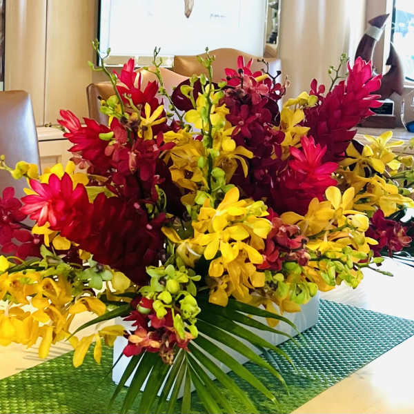 Bright red and yellow orchid arrangement in a low white container