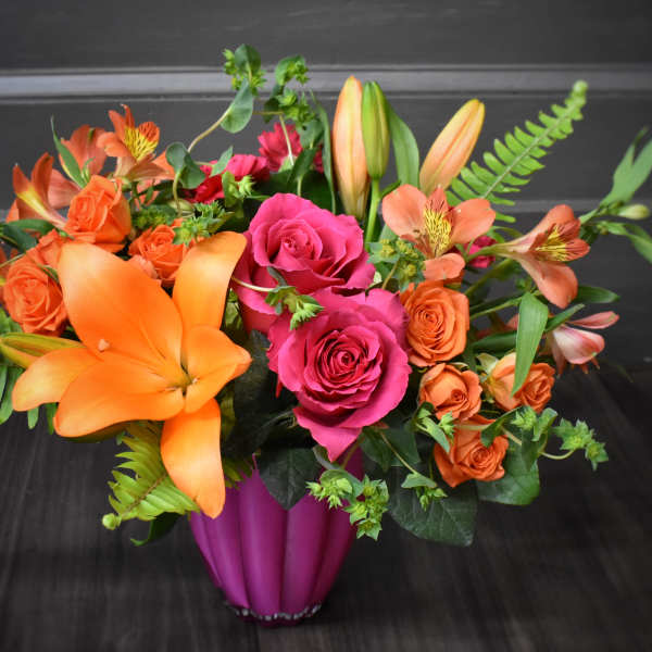 Bouquet of orange lilies and pink roses in a magenta vase