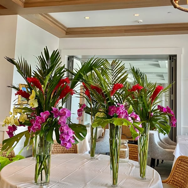 Tall tropical floral centerpieces with orchids and red blooms in glass vases