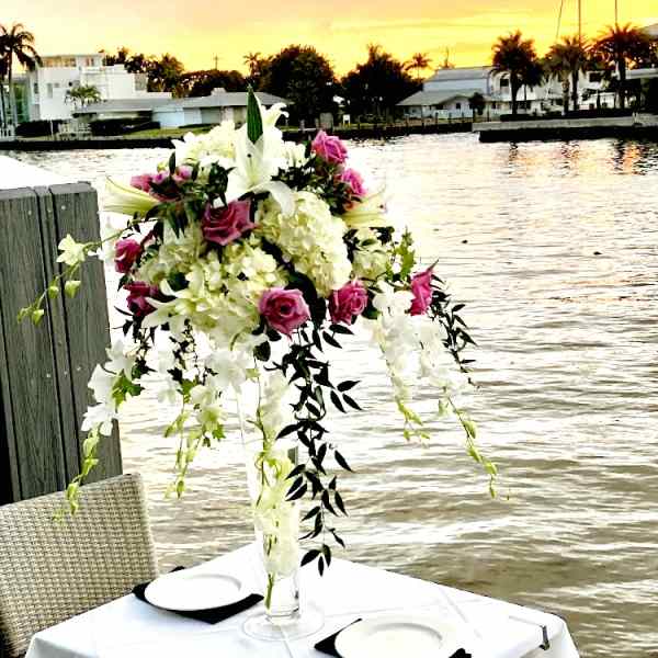 Tall floral centerpiece with pink roses and white lilies in a clear vase