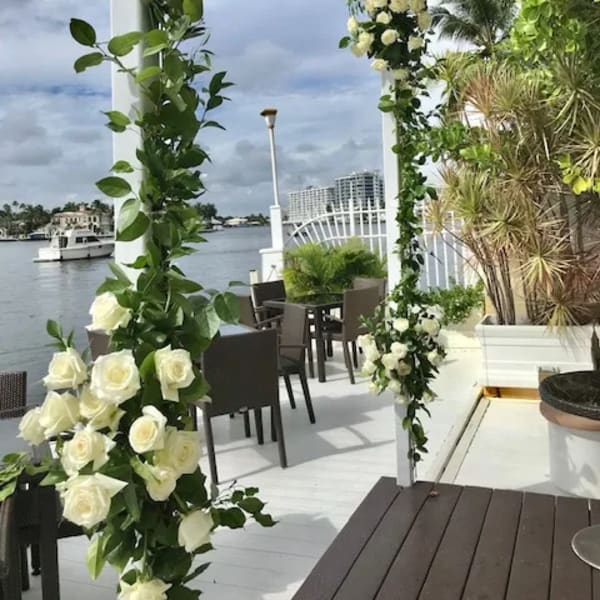 White rose floral arch on a waterfront patio