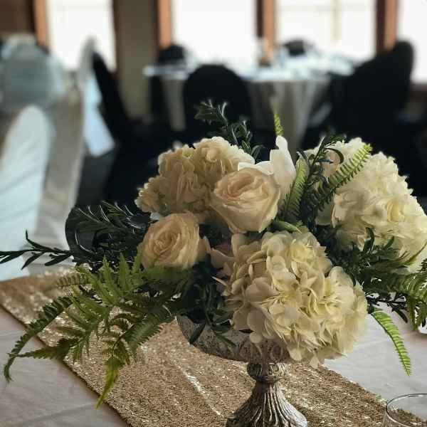 Cream floral centerpiece in a silver pedestal bowl on a table runner