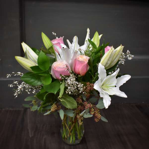 Pink roses and white lilies arranged in a clear glass vase
