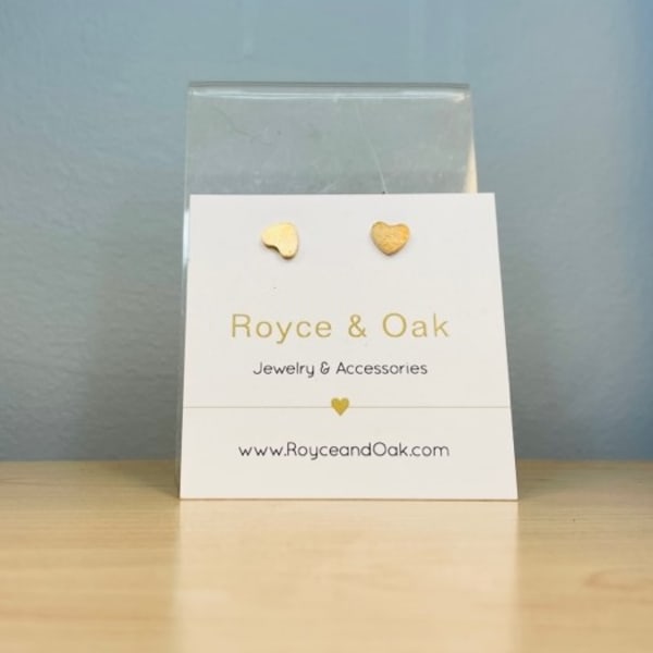 Gold heart stud earrings on a branded card in a clear sleeve