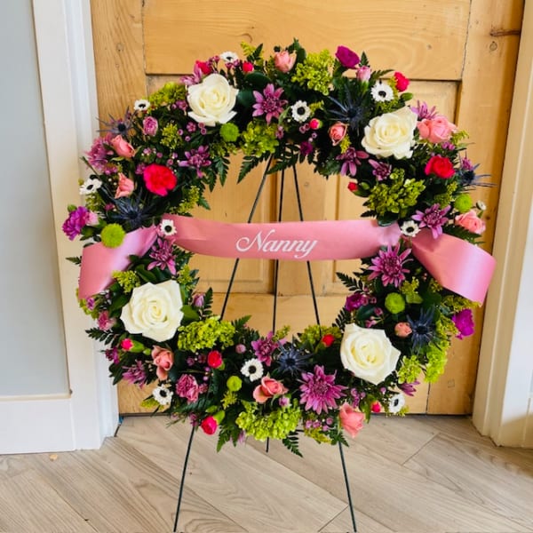 Floral wreath with pink ribbon on a stand