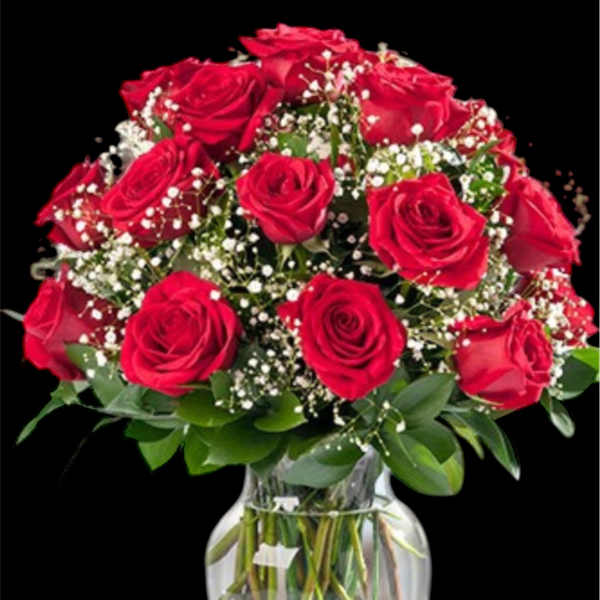Red roses arranged in a clear glass vase with baby's breath