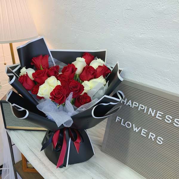 Bouquet of red and white roses wrapped in black paper