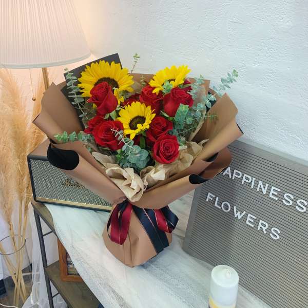 Bouquet of red roses and yellow sunflowers wrapped in brown paper