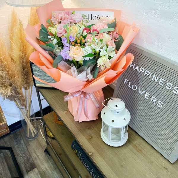 Pastel bouquet of mixed flowers wrapped in peach paper
