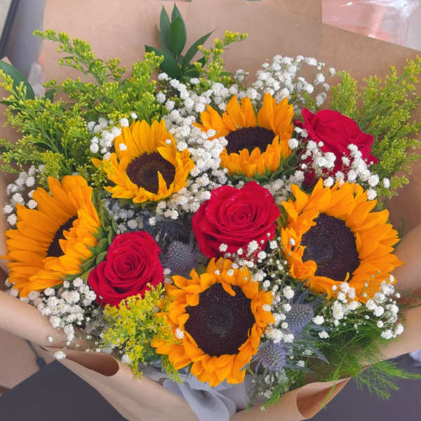 Bouquet of sunflowers and red roses wrapped in brown paper