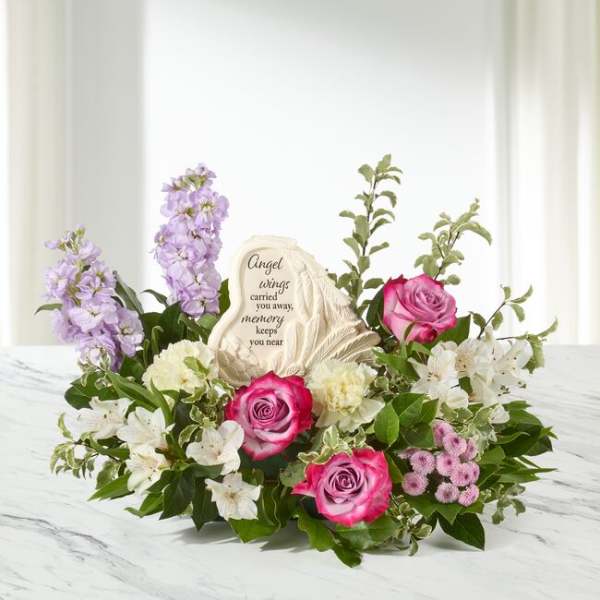 Sympathy floral arrangement with pink roses, lavender blooms, and a memorial stone