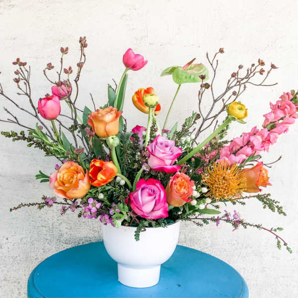 Mixed bouquet of roses, tulips, and snapdragons in a white vase