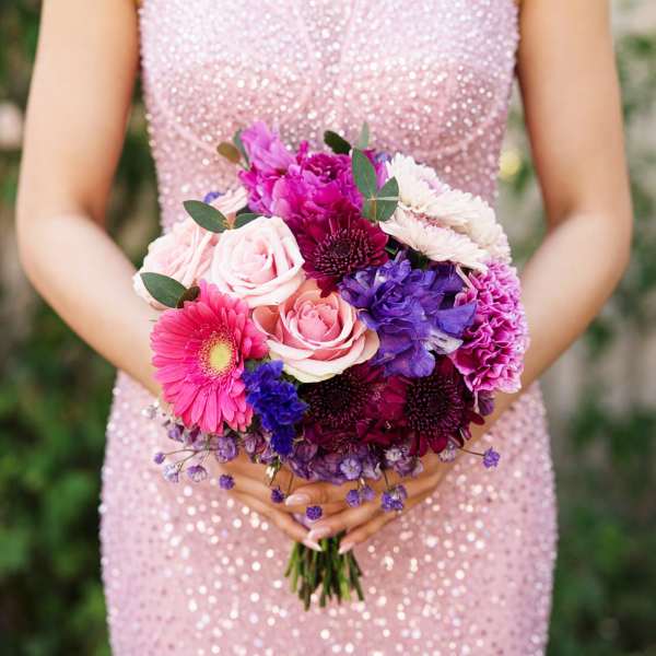 Woman holding a bouquet of pink, purple, and white flowers
