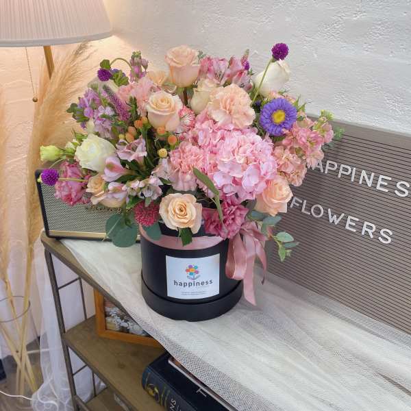 Pink and peach flower arrangement in a black hat box