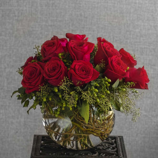 Red roses arranged in a clear glass bowl vase