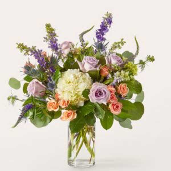 Lavender roses and purple flowers in a clear glass vase