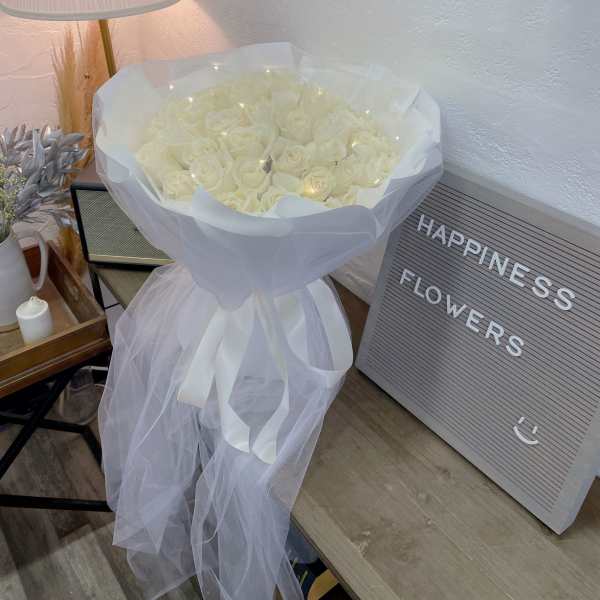 Bouquet of white roses wrapped in sheer tulle with a ribbon