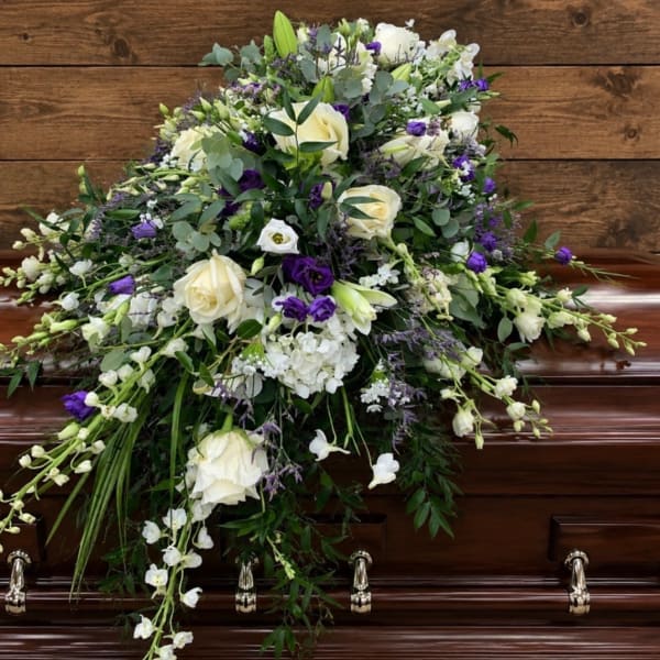White and purple floral spray arranged on a casket