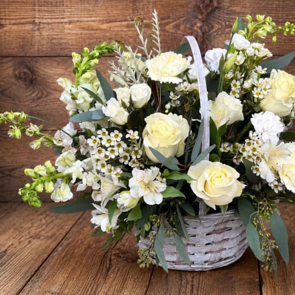 White and pale yellow flower arrangement in a white wicker basket