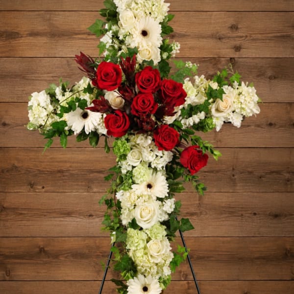 Cross-shaped floral arrangement with red and white flowers on a stand
