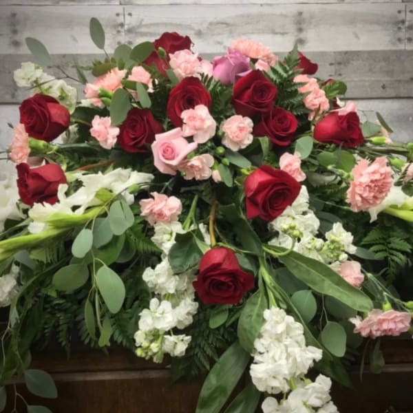 Casket spray with red roses, pink carnations, and white flowers