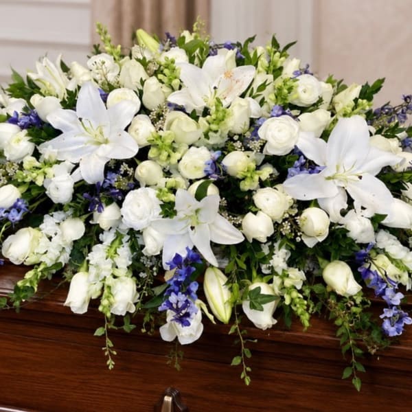 White and blue floral spray on a wooden casket
