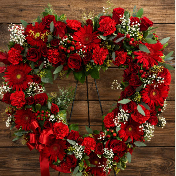 Heart-shaped red floral wreath on an easel with a ribbon bow