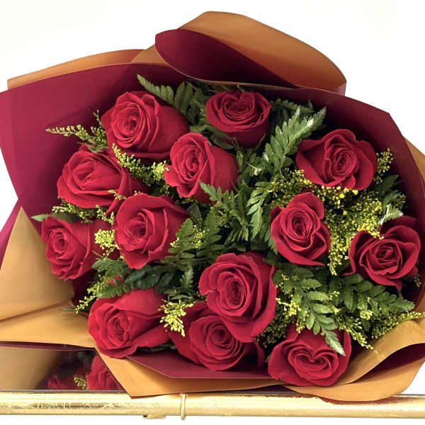 Hand-tied bouquet of red roses with fern accents wrapped in burgundy and gold paper