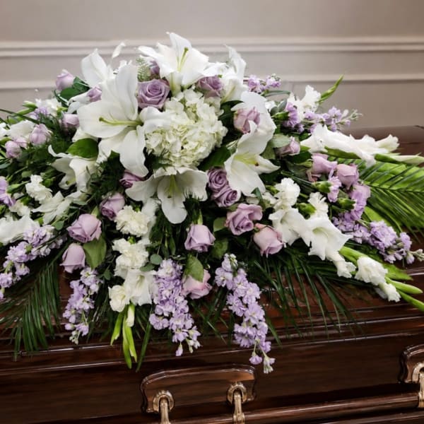 White lilies and lavender roses arranged on a casket