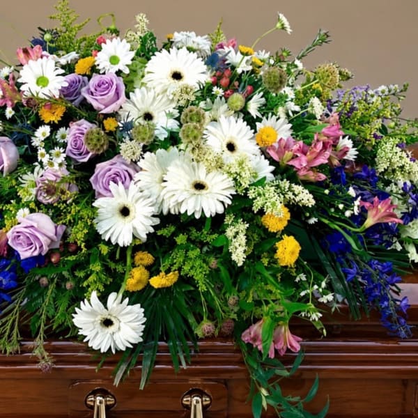 Large casket spray with white daisies, lavender roses, and mixed blooms