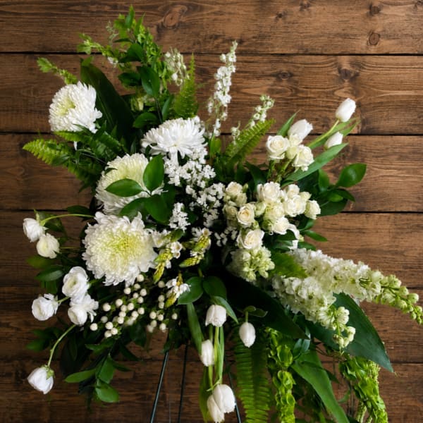 White floral standing spray on a metal easel