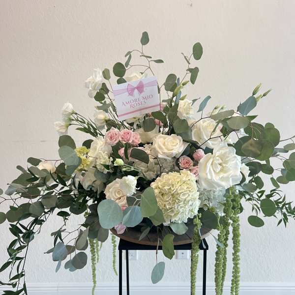 Large white and pink rose arrangement with eucalyptus and trailing greenery