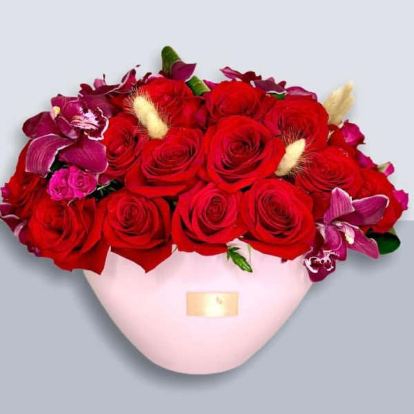 Red roses and purple orchids in a pink heart-shaped box