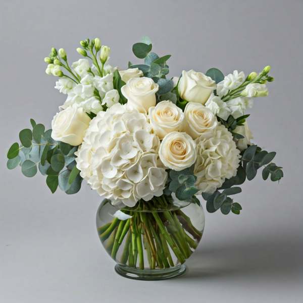 White roses and hydrangeas in a round glass vase with eucalyptus