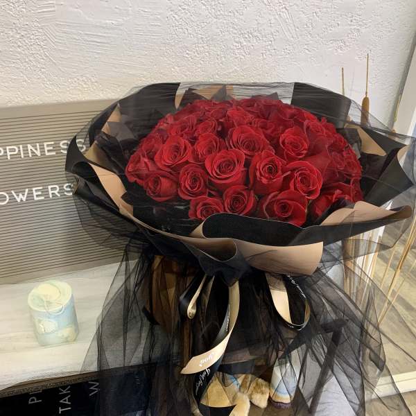 Large bouquet of red roses wrapped in black and beige tulle