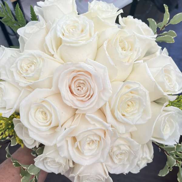 Bouquet of white roses with small green foliage accents