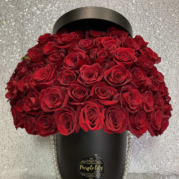 Large bouquet of red roses in a black hatbox with pearl trim