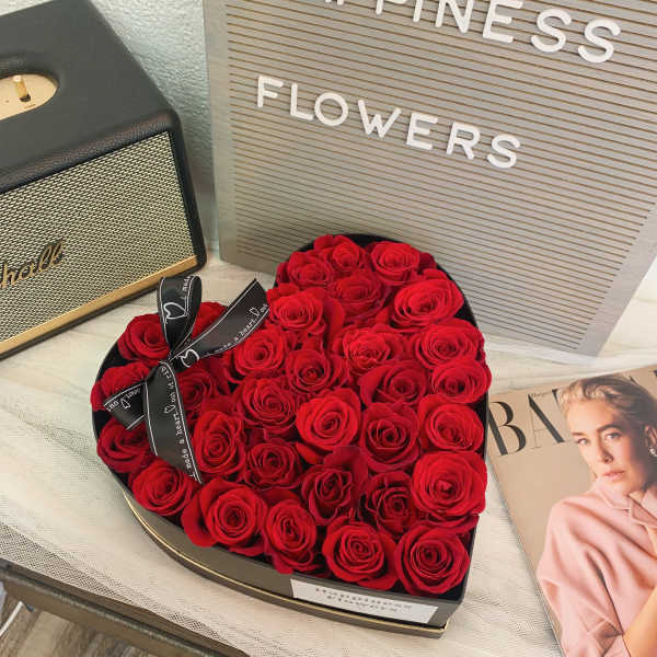 Heart-shaped box filled with red roses and a ribbon bow