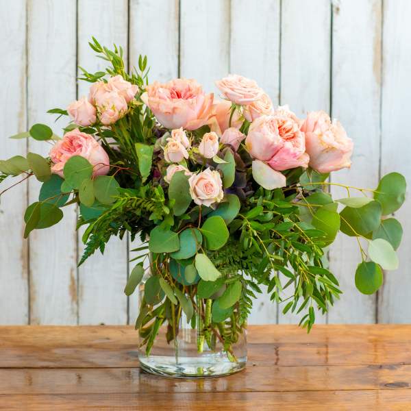 Pink roses in a clear glass vase with eucalyptus