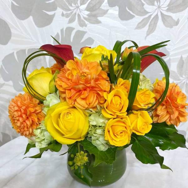 Yellow roses and orange dahlias in a green vase