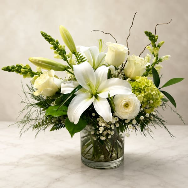 White lilies and roses arranged in a clear glass vase