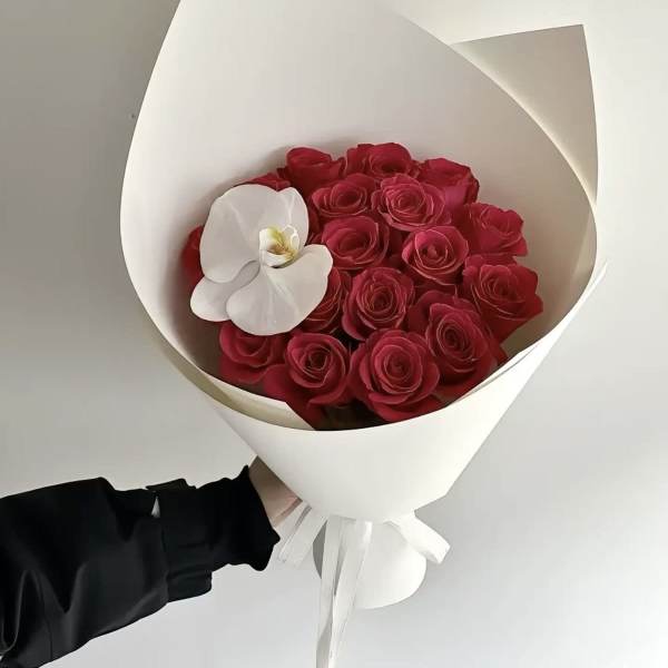 Bouquet of red roses with a white orchid in white wrap