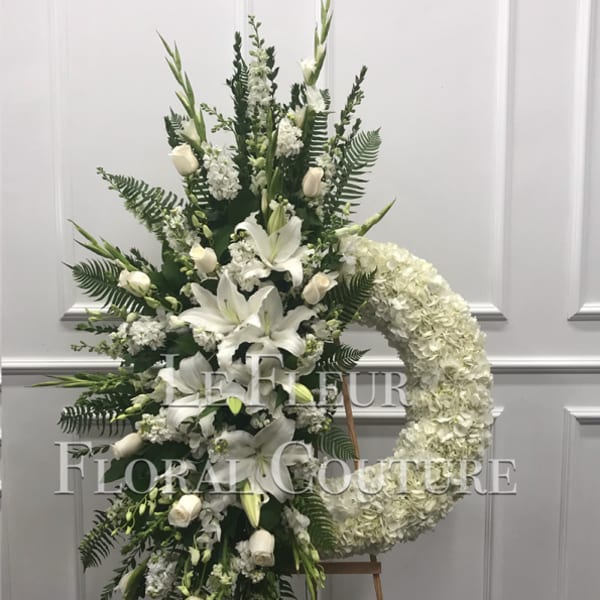 White funeral spray with lilies, roses, and a hydrangea wreath