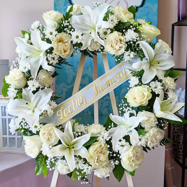 White floral wreath on an easel with a "Loving Memory" ribbon