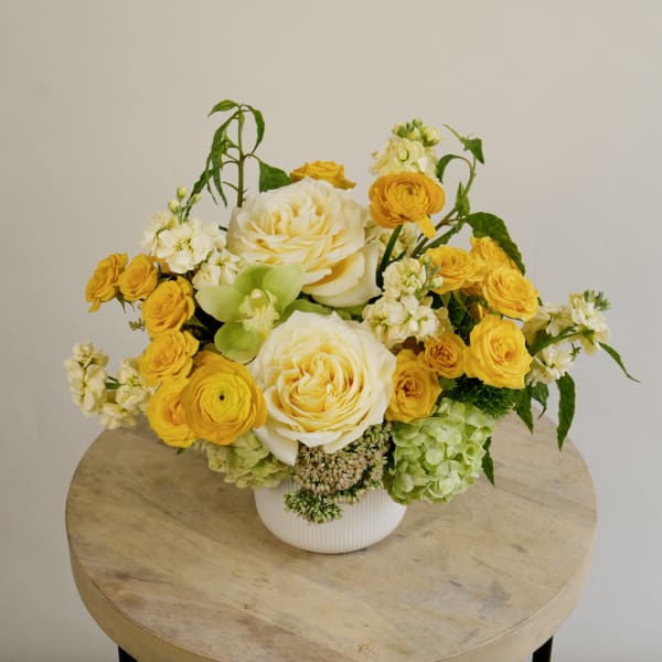 Yellow and white floral arrangement in a white vase