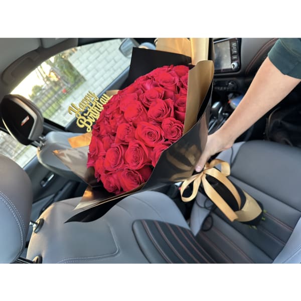 Bouquet of red roses with a gold "Happy Birthday" topper